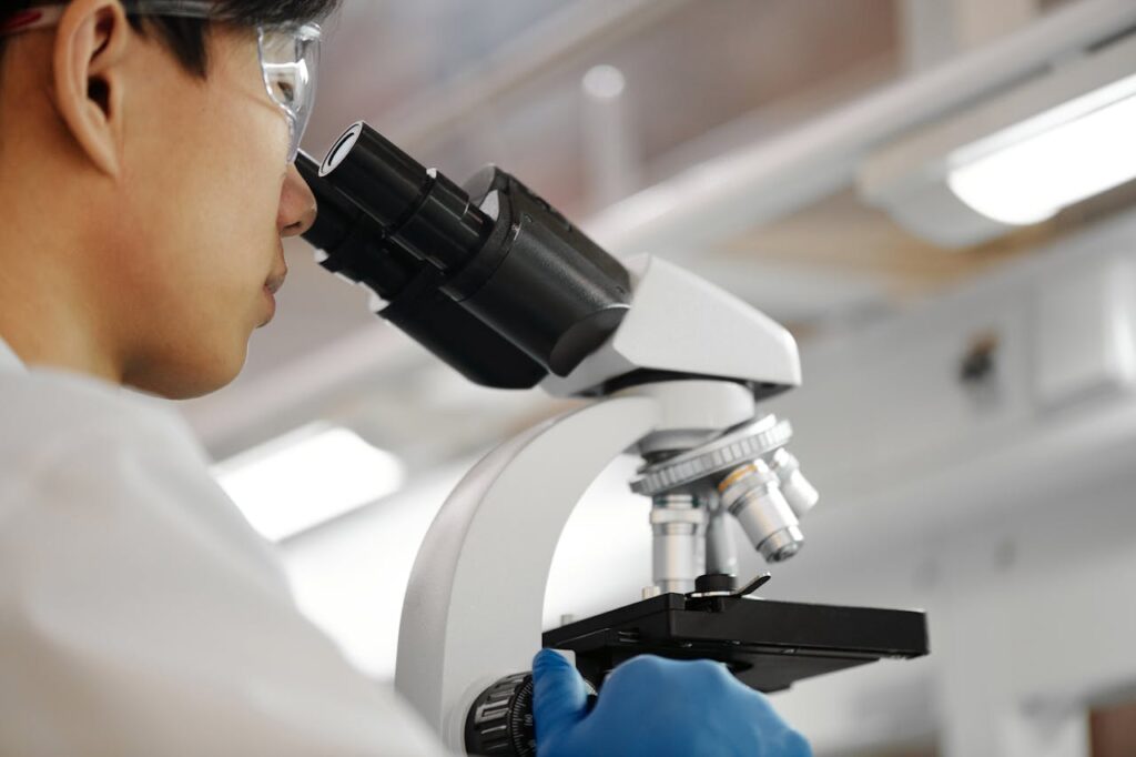 Male scientist studies samples under microscope in modern laboratory setting.